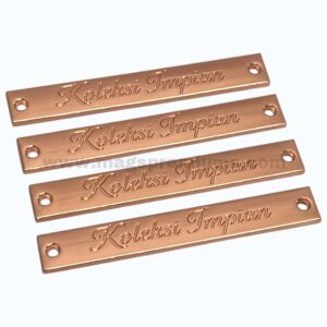 Rose gold custom metal tags with engraved logo for apparel branding.